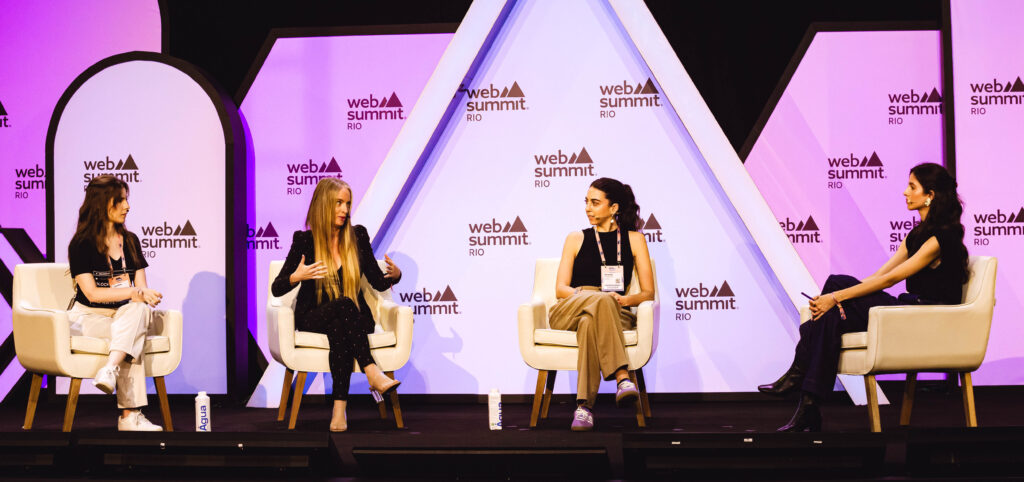 Sitting in four individual chairs on stage at Web Summit Rio are, from left to right, Debora Kantt, director of foresight and future at JPMorgan Chase & Co; Caroline Nunes, founder and chief product office at Infratoken; Rafaela Frankenthal, co-founder and CEO of SafeSpace; Ana Lankes, Latin America correspondent at The Economist.